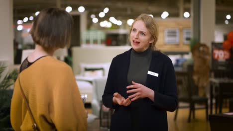 smiling female salesperson gives business card and thanks customer leaving store