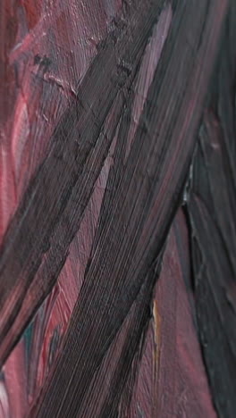 drawing of black smears on canvas fixed on easel with colorful painting using brush at art lesson in contemporary studio extreme closeup slow motion