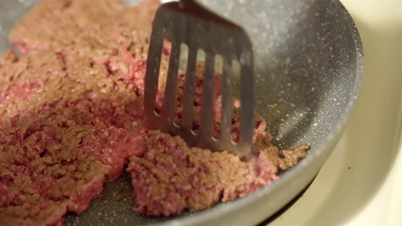 Close-up of breaking up ground beef with spatula in frying pan