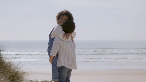 cute american boy holding and hugging his little sister at the beach on a sunny day