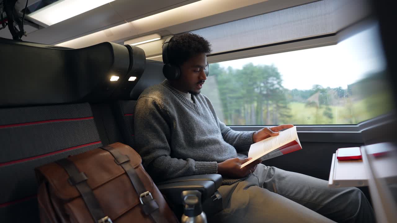 Man reading on a train with headphones