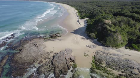 ocean waves splashing on the beach in wenonah head, urunga, australia - drone shot