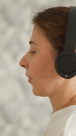 una mujer protege los ojos con auriculares mientras corre en el interior. una mujer atlética disfruta de auriculares cuando se entrena en la cinta de correr en el gimnasio. diversión durante el ejercicio