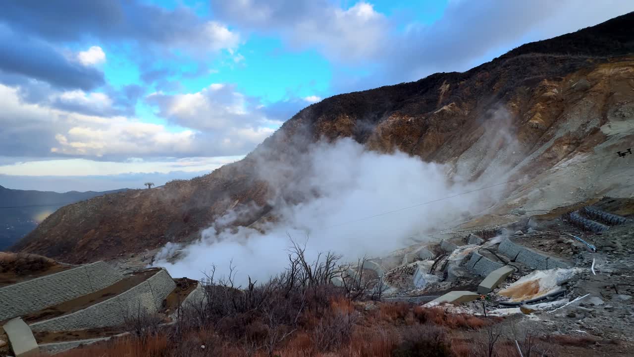 A steaming volcanic valley with rugged mountains and dramatic clouds in Owakudani Hakone