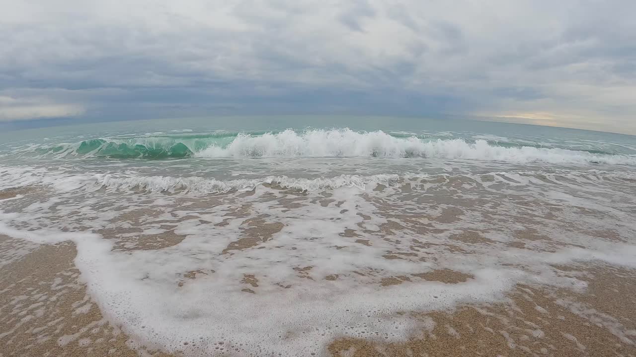 ola de mar de playa de arena gruesa en cámara lenta a 120fps 4k día nublado agua turquesa olas de mar individuales gran playa vacía