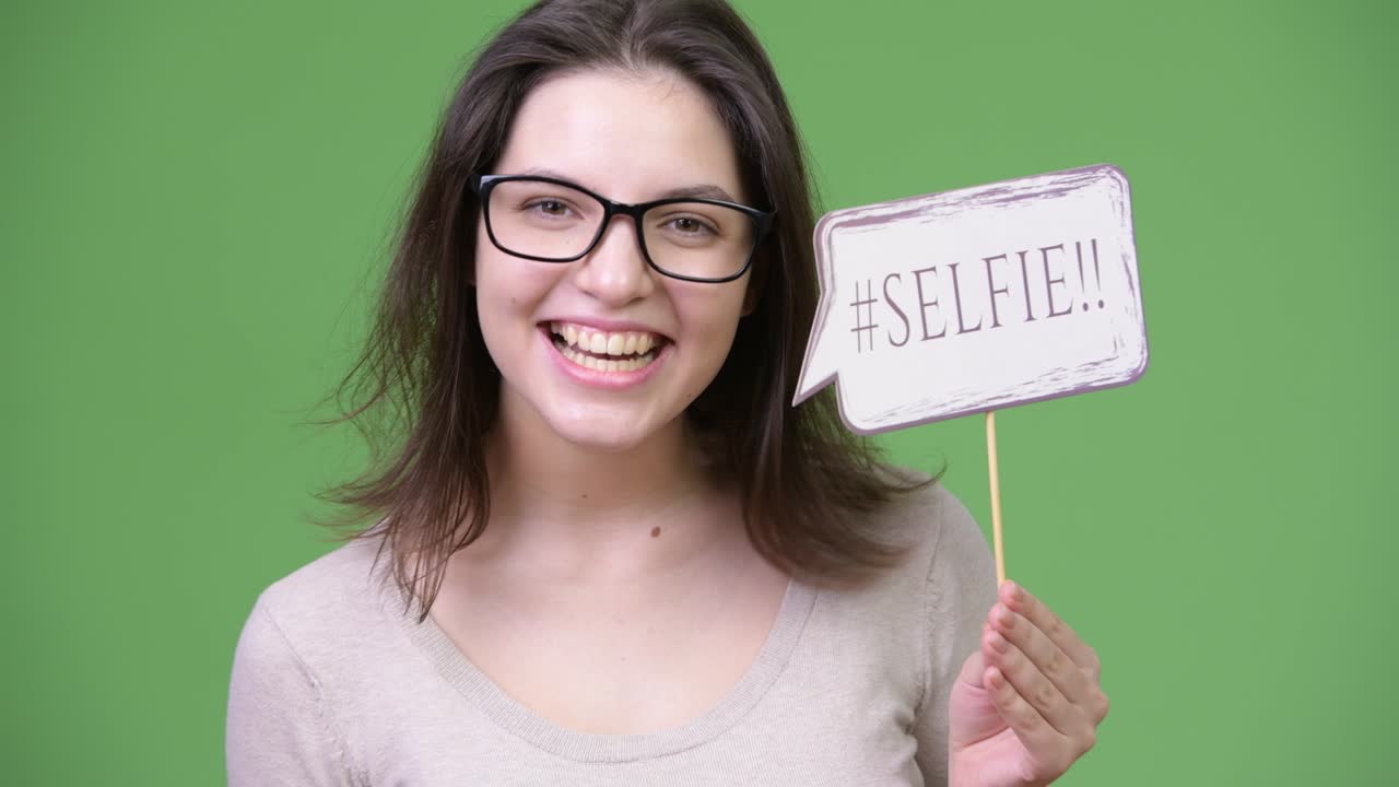 Young beautiful woman shouting while holding selfie paper sign