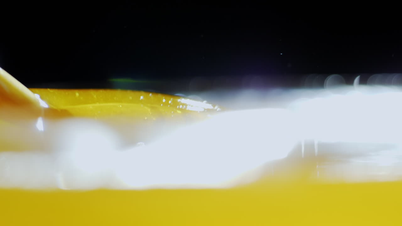 백라이트 꿀에 나무 숟가락을 담그십시오. 꿀은 빛에 아름답게 빛나고 눈부시게 빛납니다.