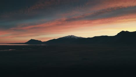 incredible and gorgeous drone and aerial shot of the setting sun against a gorgeous snow capped mountain range