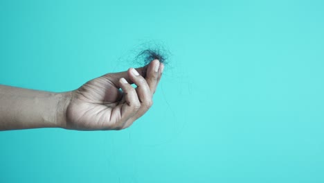 close-up of a hand holding a clump of hair, possibly showing hair loss