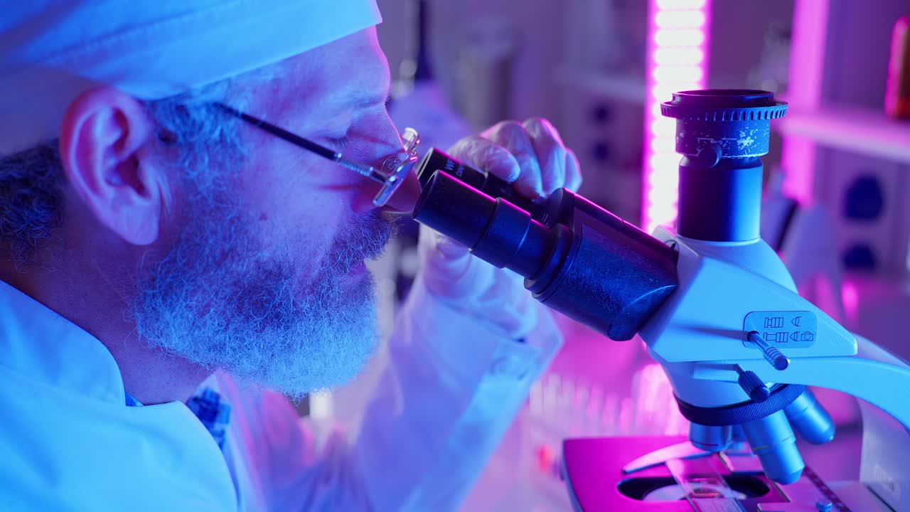 Miespuolinen tutkija katsoo mikroskoopin läpi modernissa laboratoriossa
