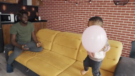 père afro-américain jouant avec son petit garçon, jetant un ballon, au ralenti