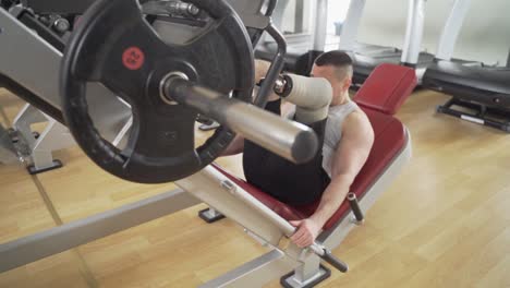 disabled athletic with leg prothesis does heavy workout for his legs at the gym