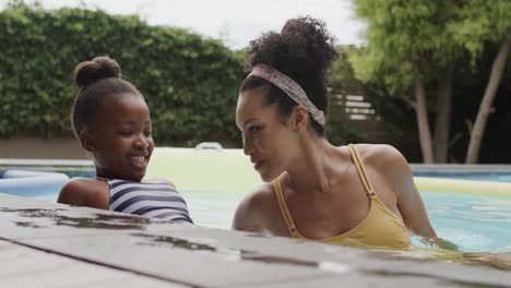 Glückliche-Afroamerikanische-Mutter-Und-Tochter-Spielen-Im-Schwimmbad-Im-Garten,-Zeitlupe