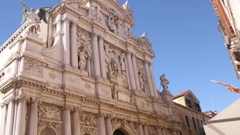 the ornate facade of a historic baroque church in venice, italy, under a bright blue sky