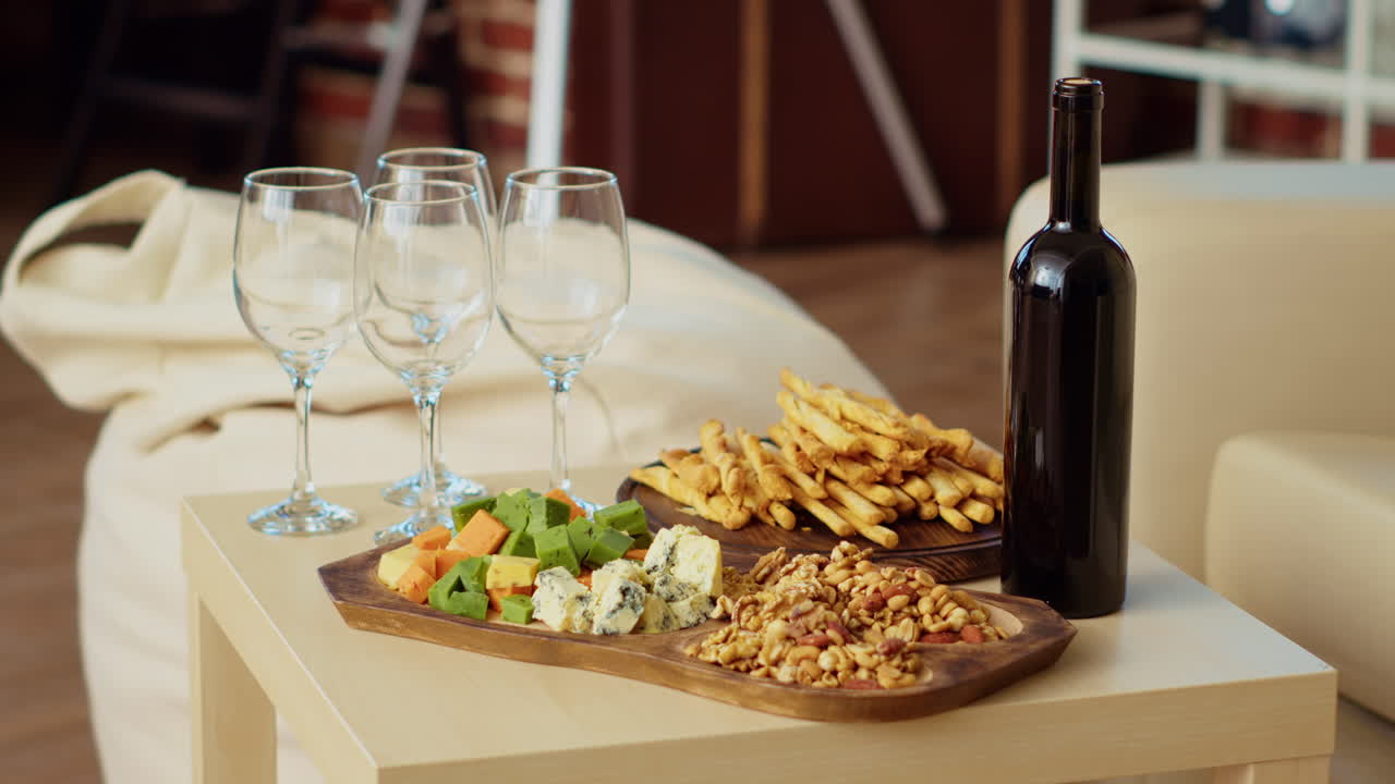 Vinflaske og glas ved siden af appetitvækkere i stuen
