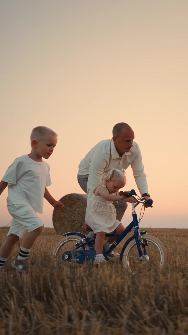 Padre che insegna alla figlia piccola ad andare in bicicletta in un campo