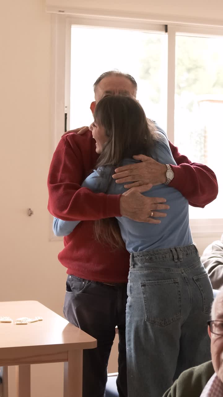 Senior man hugging and kissing granddaughter at nursing home