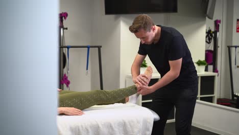 therapist massaging foot of patient in clinic