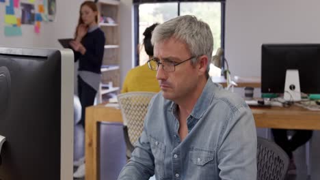 caucasian man looking at computer screen in creative office