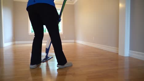 someone cleaning a wooden floor in an empty house