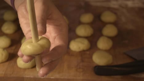 making holes in the cookie dough to model them as doughnuts, with the use of the wooden spoon