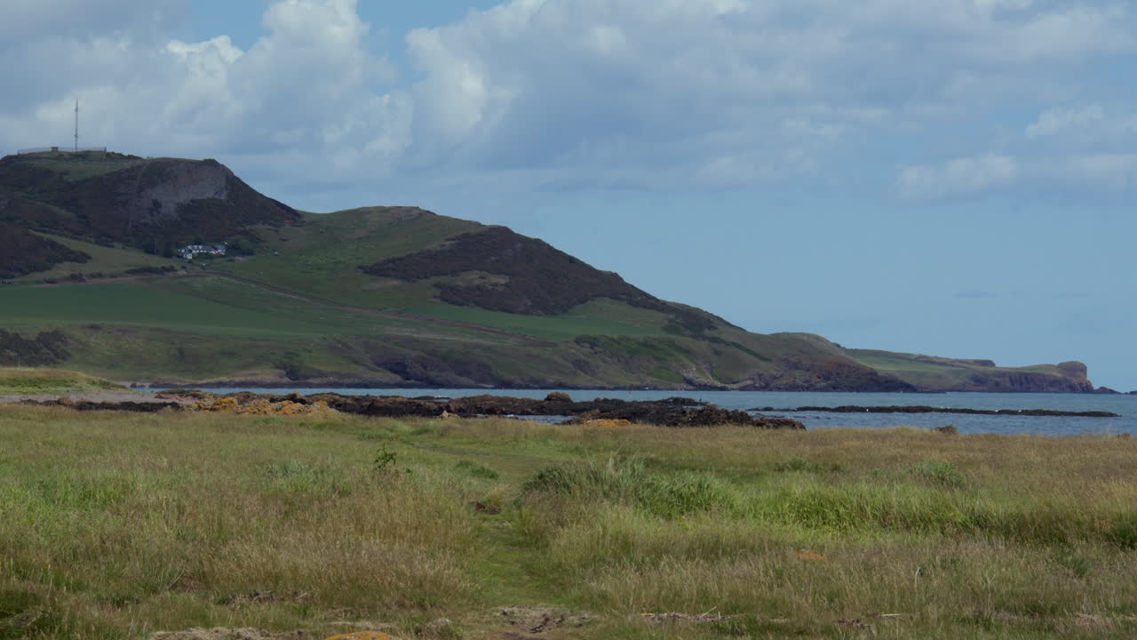 Wide shot of the hills and grassy meadows and sea north of Gourdon