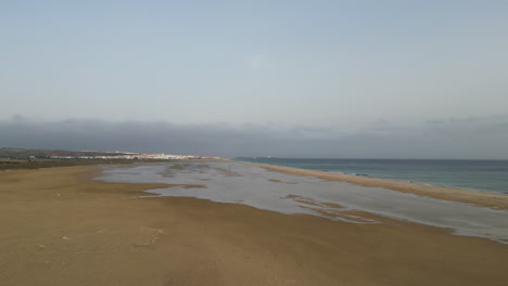 Mittlerer-Höhenflug-über-Strandlagune-In-Richtung-Meer-Mit-Afrika-Im-Hintergrund