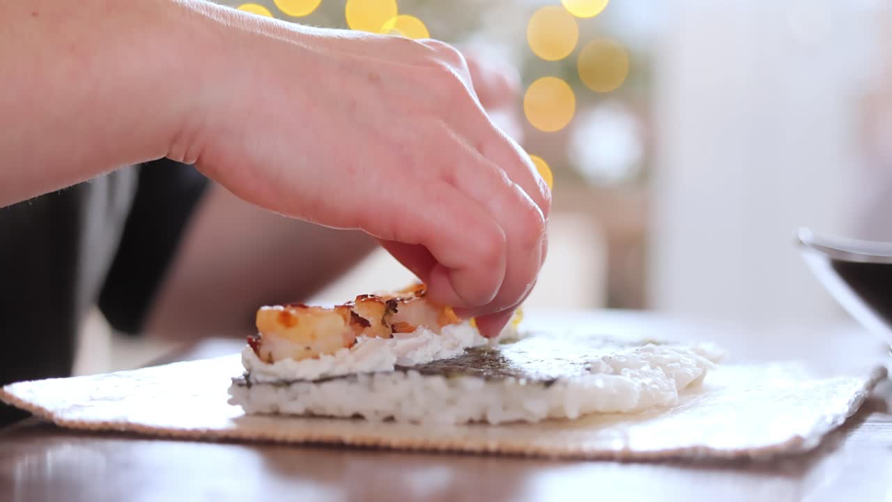 hacer sushi en la cocina de casa. manos de mujer enrollando sushi casero.