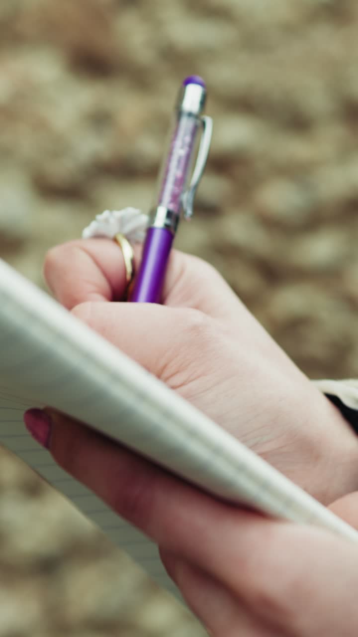Primo piano delle mani di una donna con una penna viola sulla carta