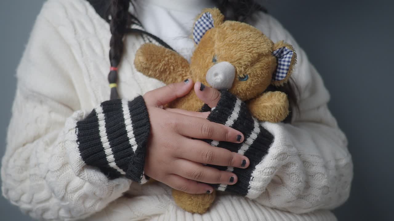Child's Hands Gently Holding a Soft Teddy Bear