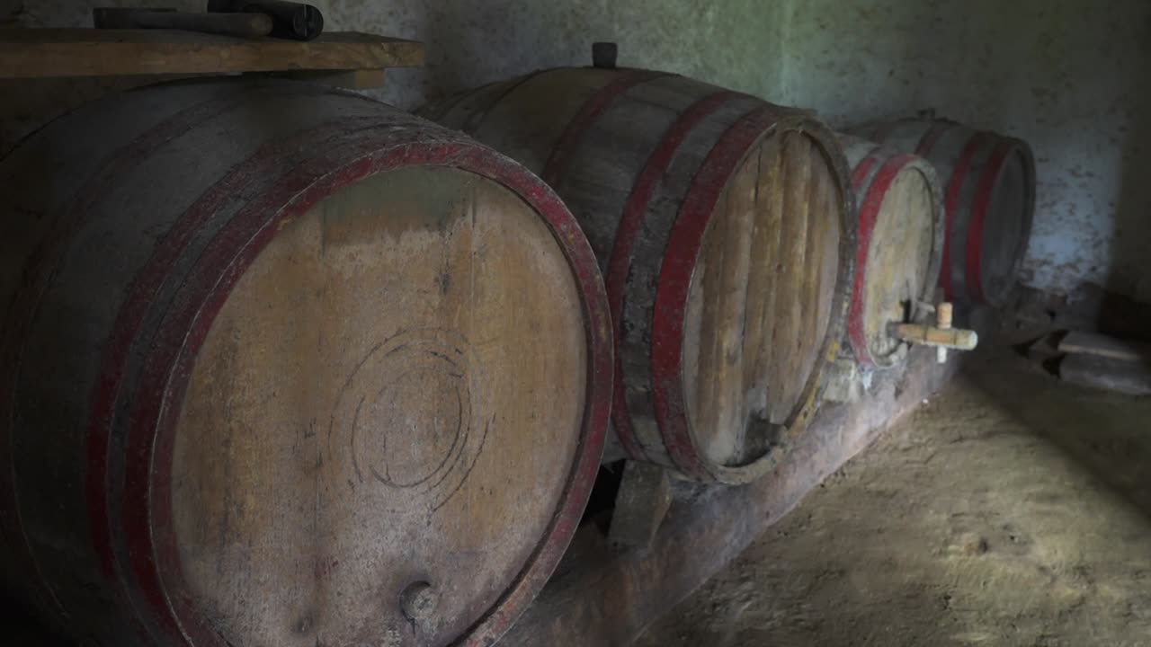 Aged wooden wine barrels lined up in a rustic wine cellar
