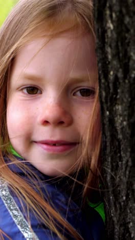 a young girl leaning against a tree