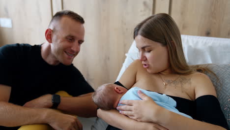 newborn baby being breastfed by mother, with father looking on