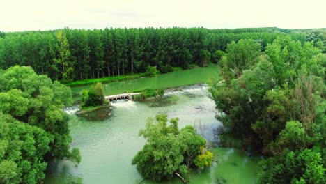 aerial clip of river in the green forest with small dam