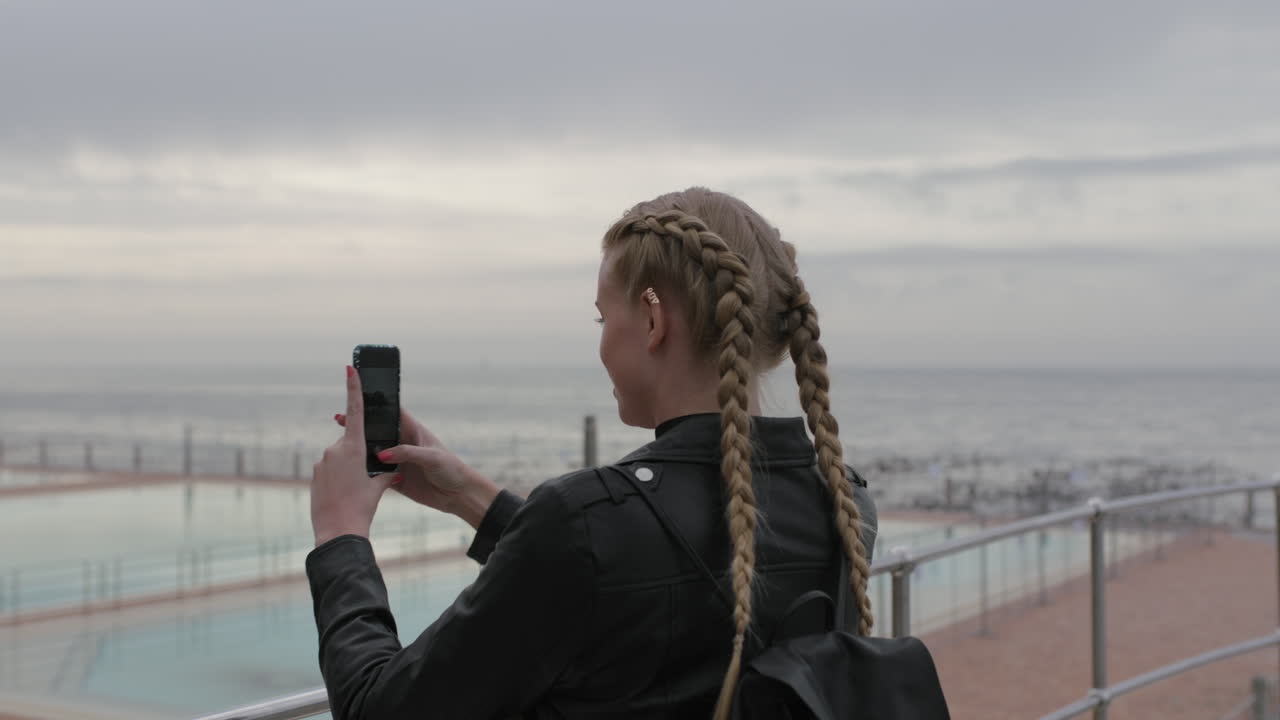mujer rubia atractiva tomando fotos usando el teléfono