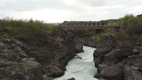 Schwenk--Und-Kippaufnahmen-Der-Flüsse,-Die-Vom-Barnafoss-Wasserfall-Kommen,-Zeigen-Auch-Eine-Aussichtsbrücke