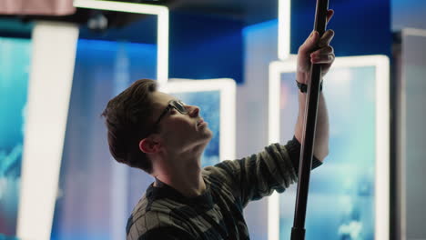 technician adjusting boom pole in broadcast studio, preparing for shot. focus on professional media production setup with camera, lighting, and studio environment visible