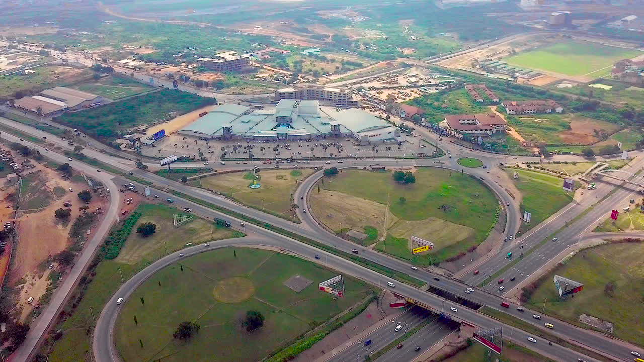 Aerial video of Accra Mall, next to the Tetteh Quarshie Interchange in Accra, Ghana, with vehicular traffic and the Villagio Building.