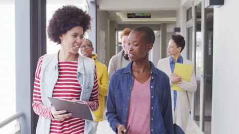 grupo diverso de colegas de negocios masculinos y femeninos caminando por el pasillo y hablando