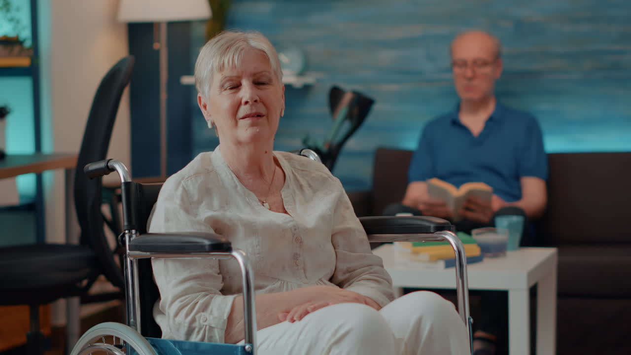 Elderly Woman in Wheelchair with Husband Reading in Living Room