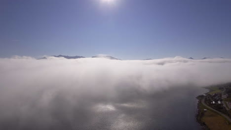 aerial of clouds drifting over a fjord