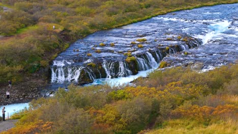 Aufschlussreiche-Luftaufnahme-Von-Touristen,-Die-Den-Wasserfall-Bruararfoss-Von-Einer-Brücke-In-Island-Aus-Beobachten