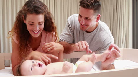 padres jugando con un bebé lindo en su cuna
