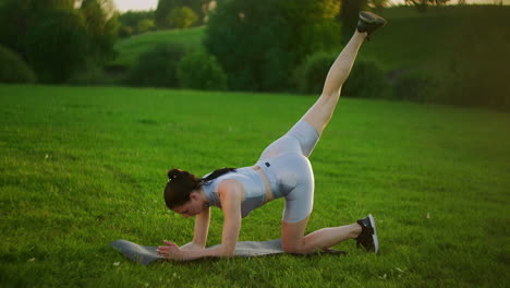 woman athlete involved in fitness in park doing leg lifts on mat. workout. work on a beautiful body in the morning or at sunset. exercises for leg and hip muscles