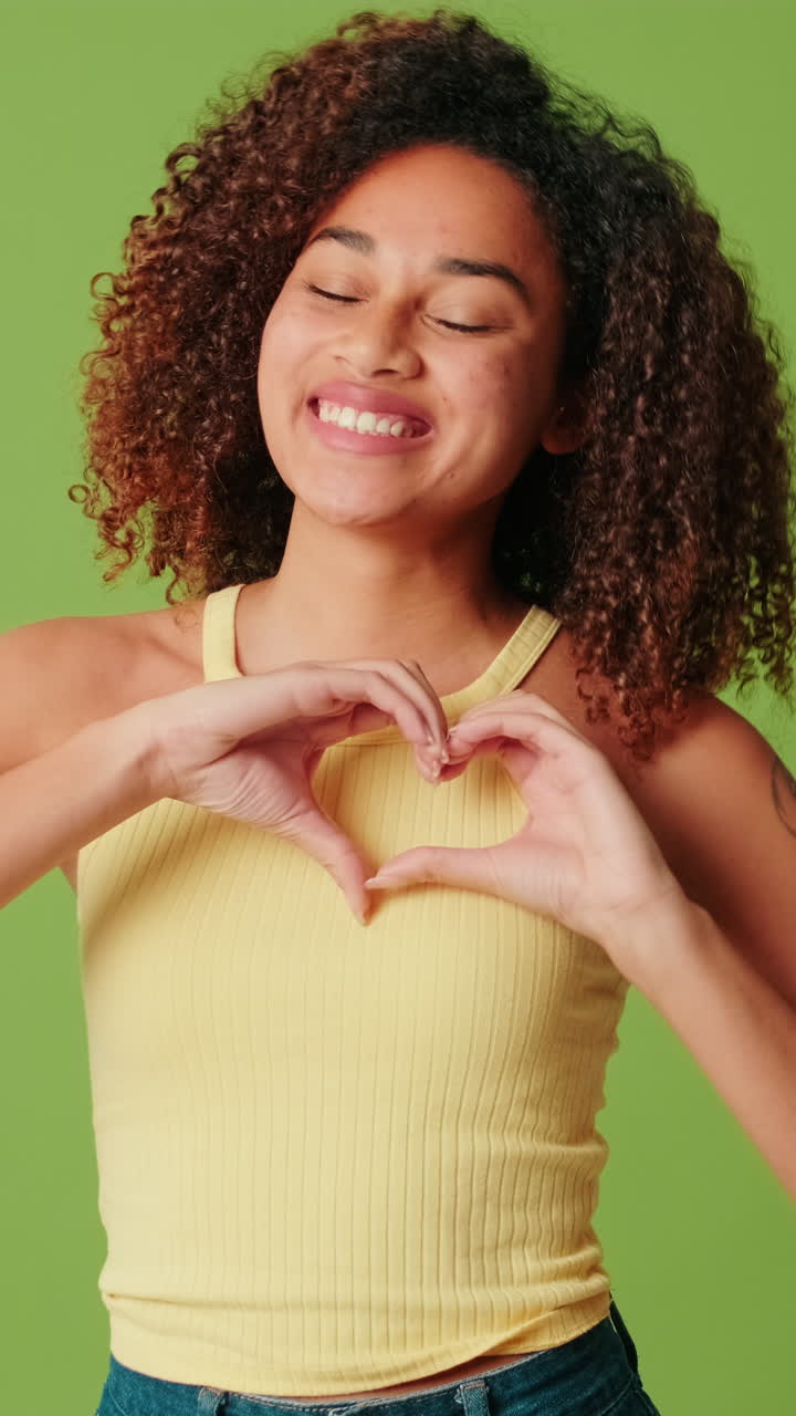 Giovane donna che fa il gesto del cuore con le mani e sorride.