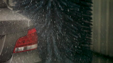 A-handheld-camera-captures-the-silver-car's-rear-end-under-the-caress-of-a-car-wash-brush