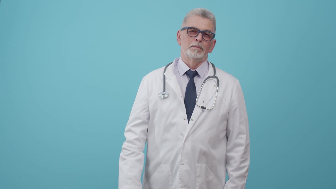 Tıbbi üniforma içindeki yetişkin erkek doktor, stüdyoda mavi bir arka plan üzerinde durarak ve kameraya bakarak uygulama yüklü telefonun yeşil ekranını gösteriyor. Tıp hakkında reklam ve uygulamalar konsepti