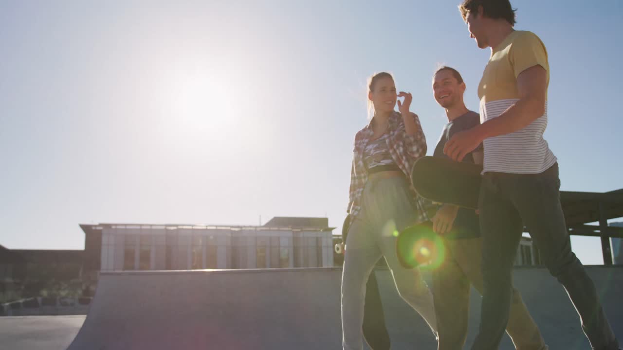 Happy caucasian woman and two male friends, walking, talking and spending time together on sunny day