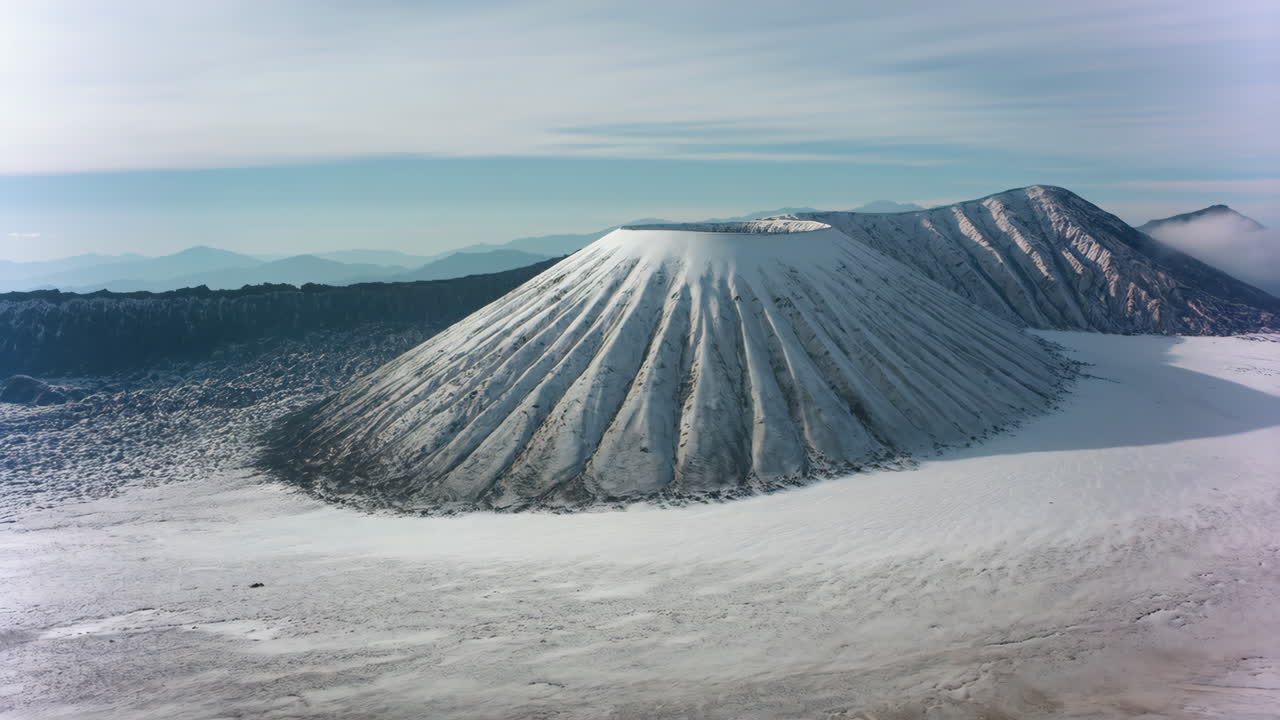 Aerial view of a large conical volcano with a wide crater