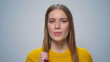 en primer plano una mujer atractiva tocando los labios con las manos sobre un fondo gris.